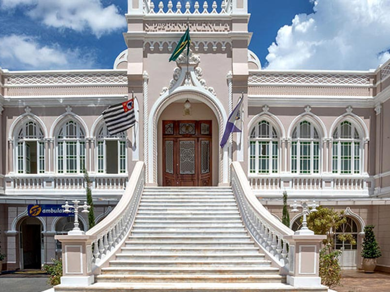 Fachada principal do Hospital São Francisco em Araraquara, com escadaria branca, portas de madeira e bandeiras do Brasil, São Paulo e da instituição.