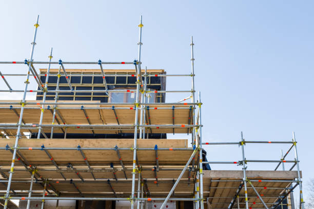 Andaimes metálicos montados ao redor de uma estrutura em construção, com plataformas de madeira e céu limpo ao fundo.